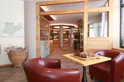 a lobby with a chess board on a table and two chairs at Alpen Garten Hotel Margherita in Rumo