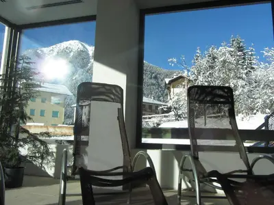 two chairs sitting in front of a window with a mountain view at Alpen Garten Hotel Margherita in Rumo