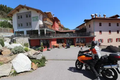 a person on a motorcycle parked in front of a building at Alpen Garten Hotel Margherita in Rumo