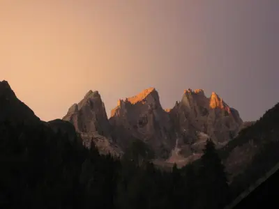 a group of mountains with the sun shining on them at Hotel Stella Alpina in Falcade