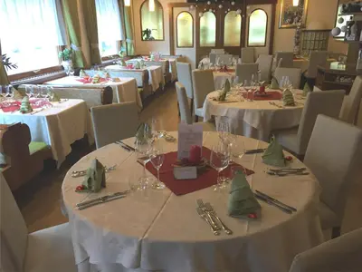 a dining room with tables with white tablecloths at Hotel Stella Alpina in Falcade
