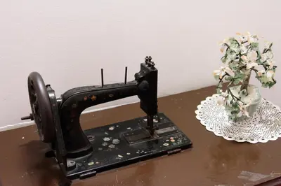a black sewing machine sitting on a table next to a vase of flowers at Hotel Stella Alpina in Falcade