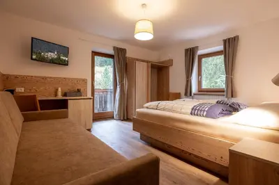 a bedroom with a bed and a couch at SAN PIETRO DOLOMITI Small Budget Hotel in Ortisei