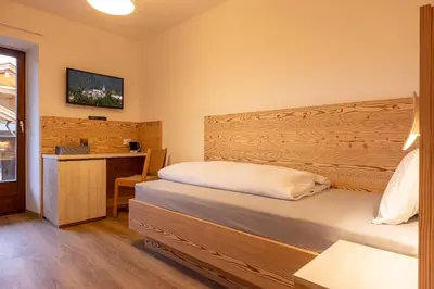 a bedroom with a bed and a desk with a television at SAN PIETRO DOLOMITI Small Budget Hotel in Ortisei