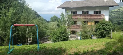 a playground in a field in front of a house at SAN PIETRO DOLOMITI Small Budget Hotel in Ortisei