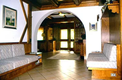a living room with two couches and an archway at Hotel Gran Mugon in Vigo di Fassa