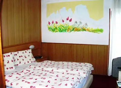 a bedroom with a bed with a painting on the wall at Hotel Gran Mugon in Vigo di Fassa