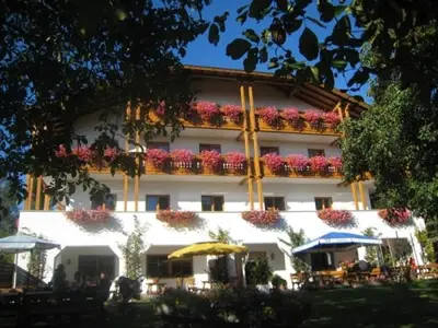 a large white building with tables and umbrellas in front of it at Hotel Mair Am Bach in Bressanone
