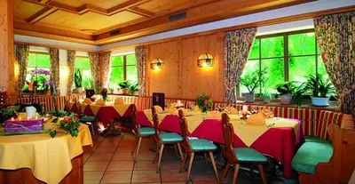 a restaurant with long tables and chairs and windows at Hotel Mair Am Bach in Bressanone