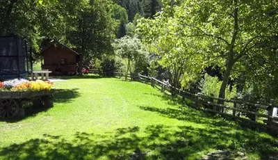 a field of grass with a fence and a barn at Hotel Mair Am Bach in Bressanone