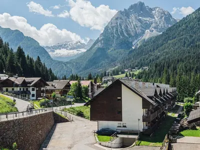 a village in a valley with mountains in the background at Residence Contrin in Canazei