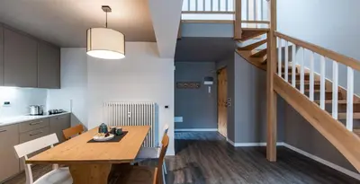 a kitchen and dining room with a wooden table and a staircase at Residence Contrin in Canazei