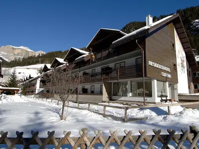 a large building with a fence in the snow at Residence Contrin in Canazei