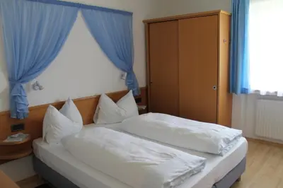 two beds in a hotel room with blue curtains at Haus Aron in Brunico