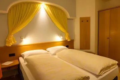 a bedroom with a large white bed with yellow curtains at Haus Aron in Brunico
