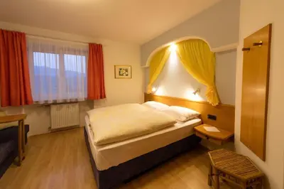 a bedroom with a large bed and two windows at Haus Aron in Brunico