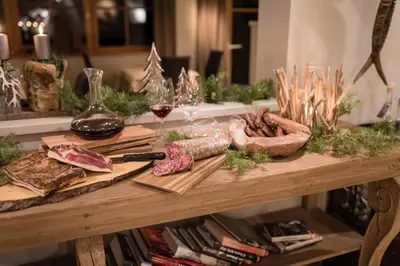a table with meats and wine glasses on it at Charme Hotel Friedrich in Nova Levante