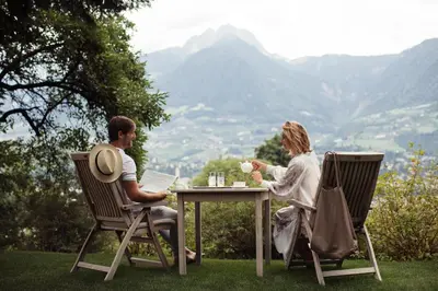 a man and woman sitting at a table with a laptop at Giardino Marling in Merano