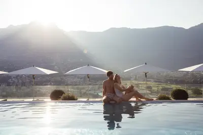 a man and woman sitting on the edge of a swimming pool at Giardino Marling in Merano