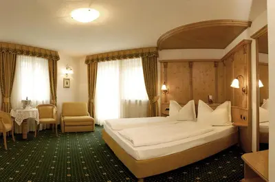 a hotel room with a large bed and a table at Hotel Maria in Ortisei