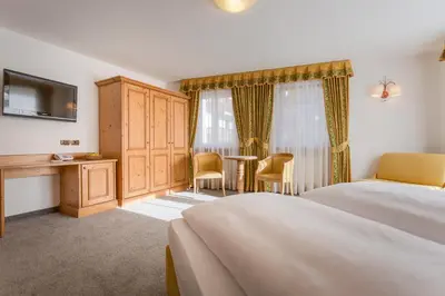 a hotel room with a bed and a table and chairs at Hotel Maria in Ortisei