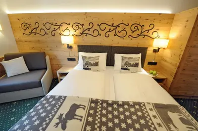 a bedroom with a large bed and a couch at Hotel Maria in Ortisei
