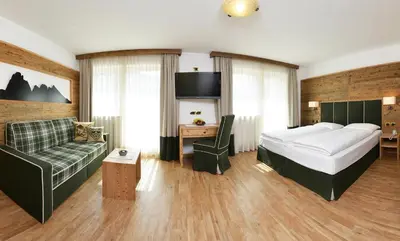 a hotel room with a bed and a couch at Hotel Maria in Ortisei