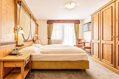 a bedroom with a large bed with a table and a desk at Hotel Maria in Ortisei
