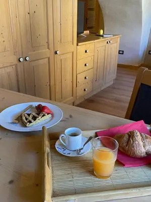 a table with a plate of food and a cup of orange juice at Agriturismo La Canonica in Brez