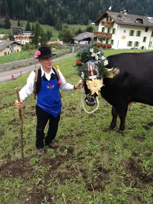 a man is standing next to a cow at Agritur Ciasa Dò Parè in Soraga