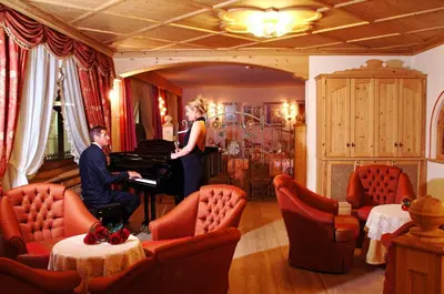 a man playing a piano in a room with a woman at Hotel Malder in Soraga