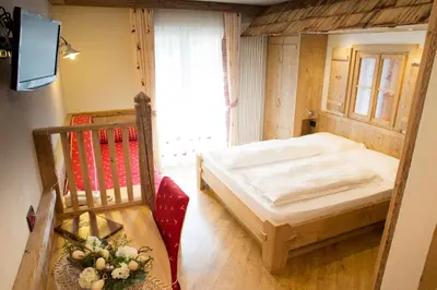 a bedroom with a bed and a chair and a television at Hotel Malder in Soraga