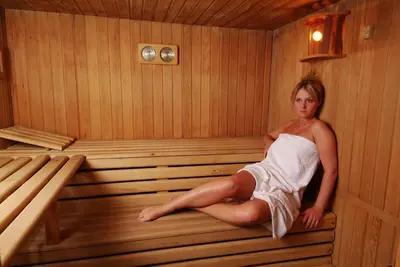 a woman is sitting in a sauna at Hotel Malder in Soraga