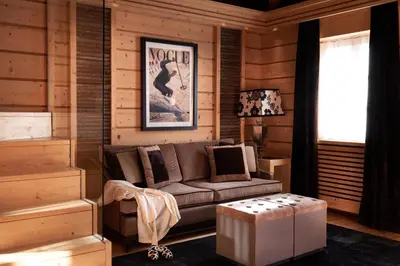 a living room with a couch and a stool at Rosapetra SPA Resort - Small Luxury Hotels of the World in Cortina dʼAmpezzo