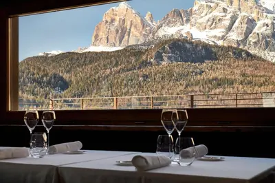 a table with wine glasses in front of a window at Rosapetra SPA Resort - Small Luxury Hotels of the World in Cortina dʼAmpezzo