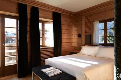 a bedroom with a white bed and two windows at Rosapetra SPA Resort - Small Luxury Hotels of the World in Cortina dʼAmpezzo