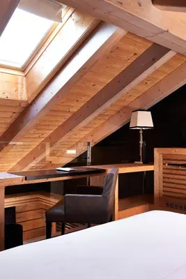 an attic room with a table and a chair at Rosapetra SPA Resort - Small Luxury Hotels of the World in Cortina dʼAmpezzo