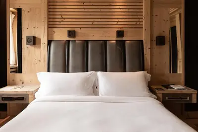 a bedroom with a large white bed and wooden walls at Rosapetra SPA Resort - Small Luxury Hotels of the World in Cortina dʼAmpezzo