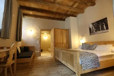 a bedroom with a bed and a desk and a chair at Agritur Ciastel in Sanzeno