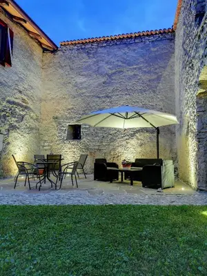 a patio with a table and chairs and an umbrella at Agritur Ciastel in Sanzeno