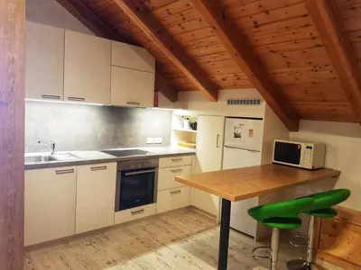 a kitchen with white cabinets and a table with a microwave at Pelegrin 15 in San Vigilio Di Marebbe