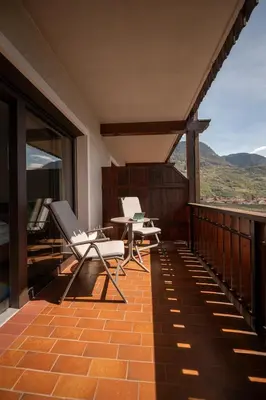a balcony with two chairs and a table with a view at Hotel Salgart in Merano