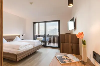 a hotel room with two beds and a balcony at Hotel Salgart in Merano