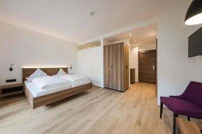 a bedroom with a large bed and a purple chair at Hotel Salgart in Merano