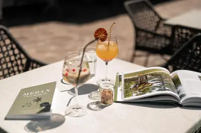 a table with a book and two glasses of wine at Hotel Salgart in Merano