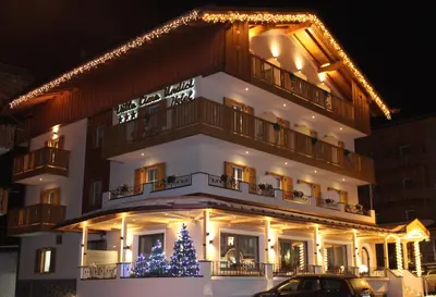 a large building with a christmas tree in front of it at Hotel Villa Cima Undici in Pozza di Fassa
