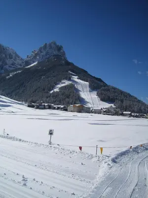 a snow covered slope with a mountain in the background at Hotel Villa Cima Undici in Pozza di Fassa
