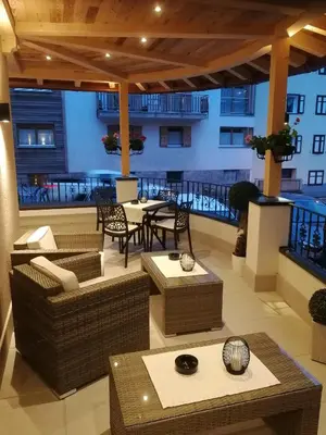 a patio with tables and chairs in a building at Hotel Villa Cima Undici in Pozza di Fassa