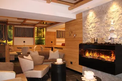a living room with a fireplace and a couch at Hotel Villa Cima Undici in Pozza di Fassa