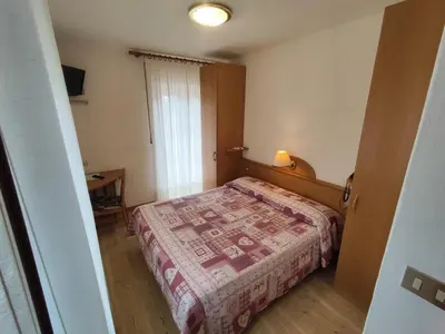a small bedroom with a bed and a window at Hotel Villa Cima Undici in Pozza di Fassa